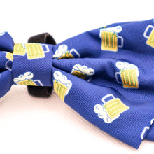 Load image into Gallery viewer, Close up picture of Bow Tie for pet collars with beer stein images on fabric.  Shows edges of velcro used to attach bow tie to collar. Bow tie is navy blue with yellow and white beer images. 
