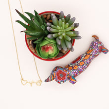 Load image into Gallery viewer, Gold tone necklace with open heart and paws connected by a heartbeat rhythm.  Diplayed on white background with mosaic dachsund figurine and succulent plant. . 
