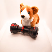 Load image into Gallery viewer, Angled view picture of Dogzilla Strong Chewer Bone dog toy.  Bone is hard black rubber with red accents.  Displayed on a white background with a stuffed corgi toy. 
