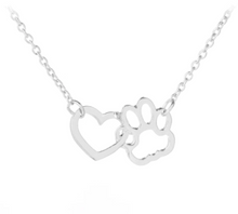 Load image into Gallery viewer, Silver tone necklace with open heart charms intertwined with open pet paw charms. Displayed on white background.
